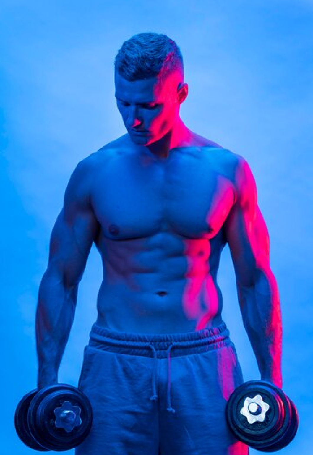 спортивный мужчина в шортах держит в руках гантели